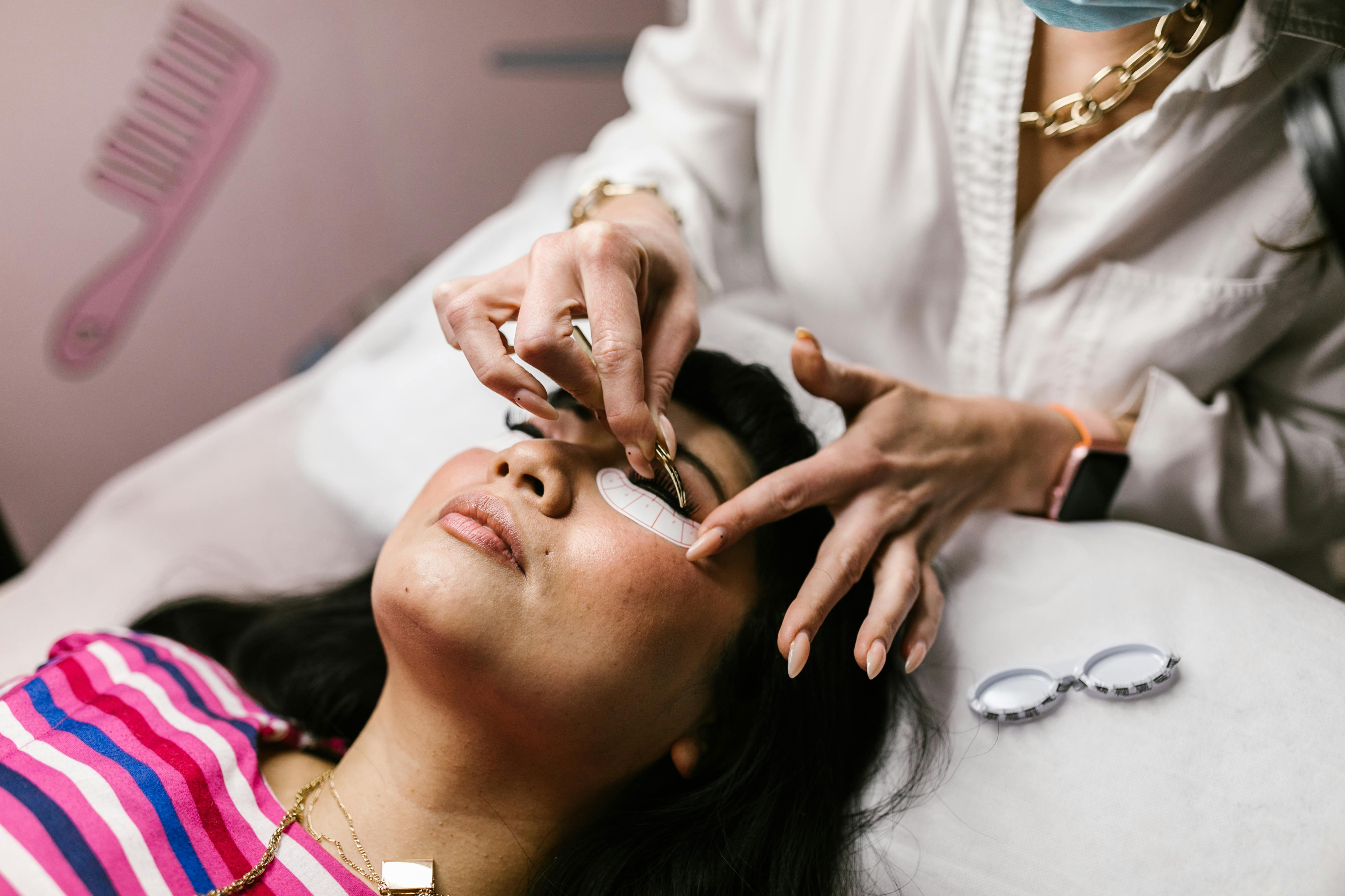 Woman receiving professional salon eyelash extensions treatment.