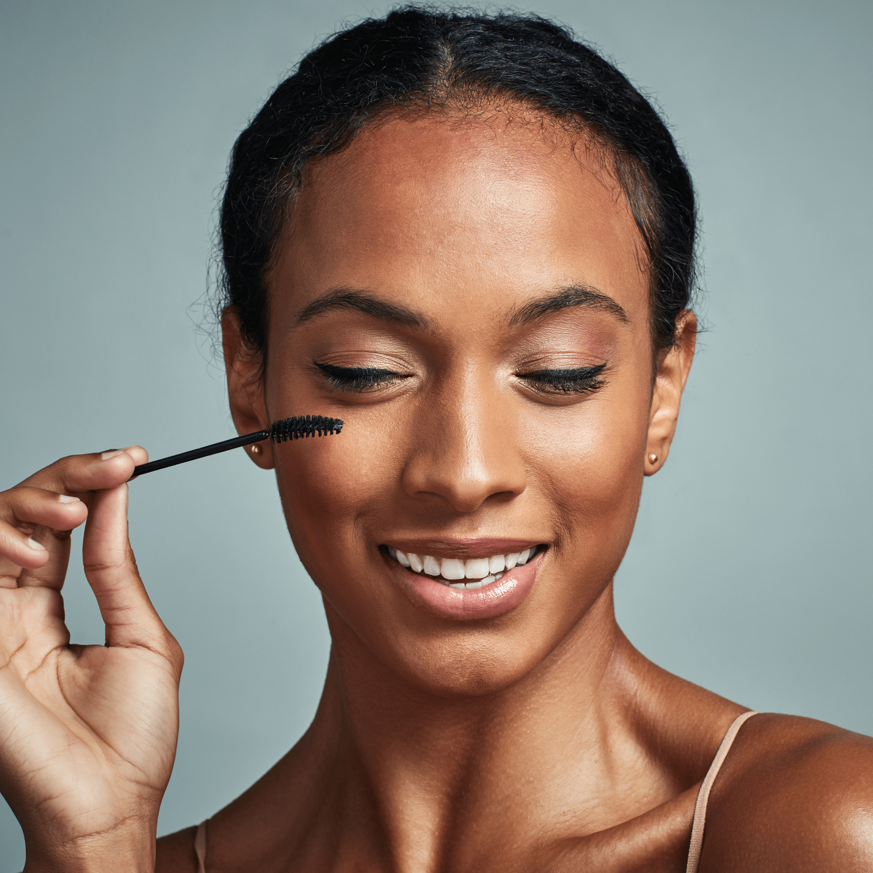 Woman applying mascara to enhance her eyelashes for a beautiful makeup look.