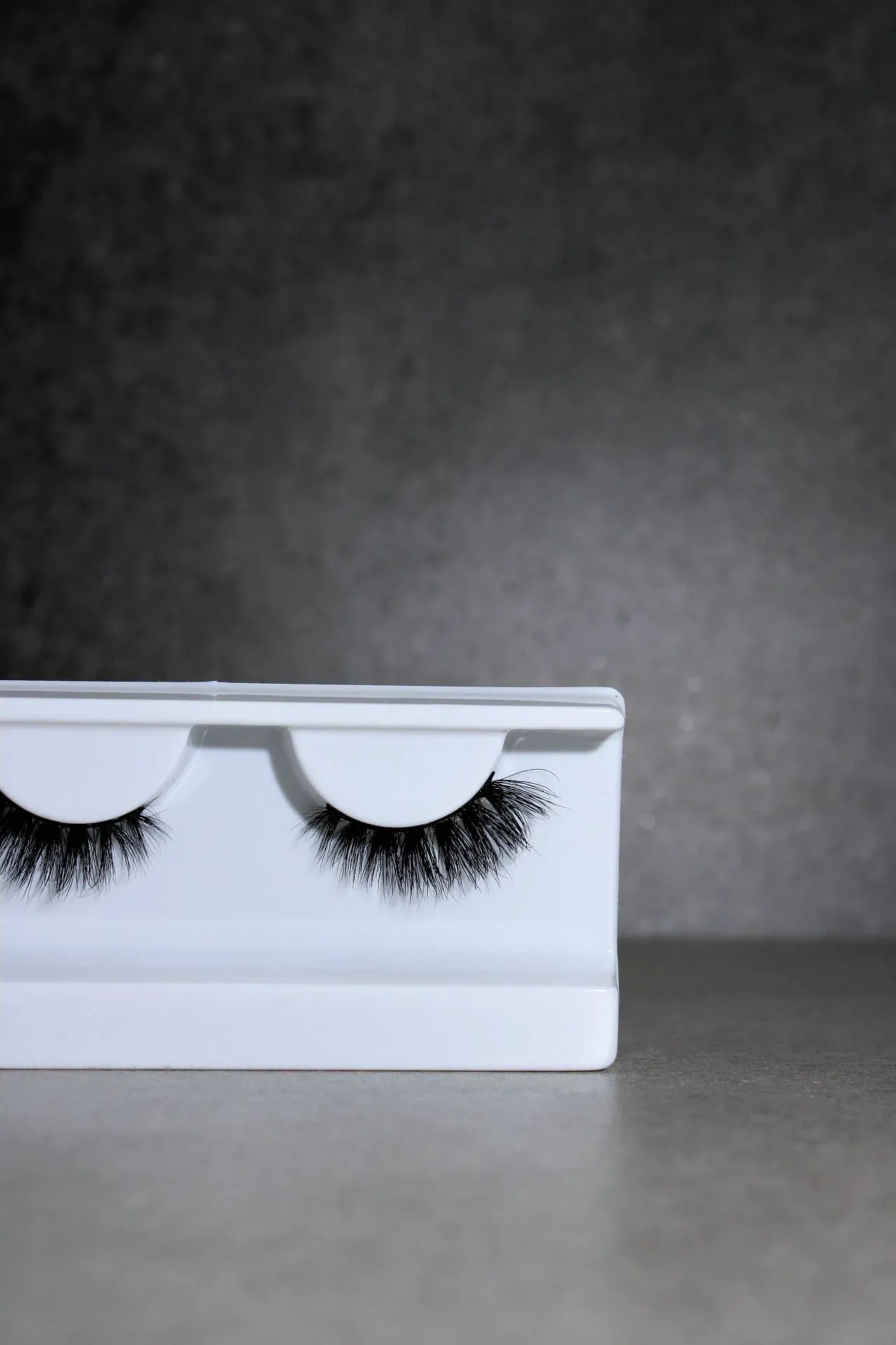 Eyelash packaging with false eyelashes on a gray background