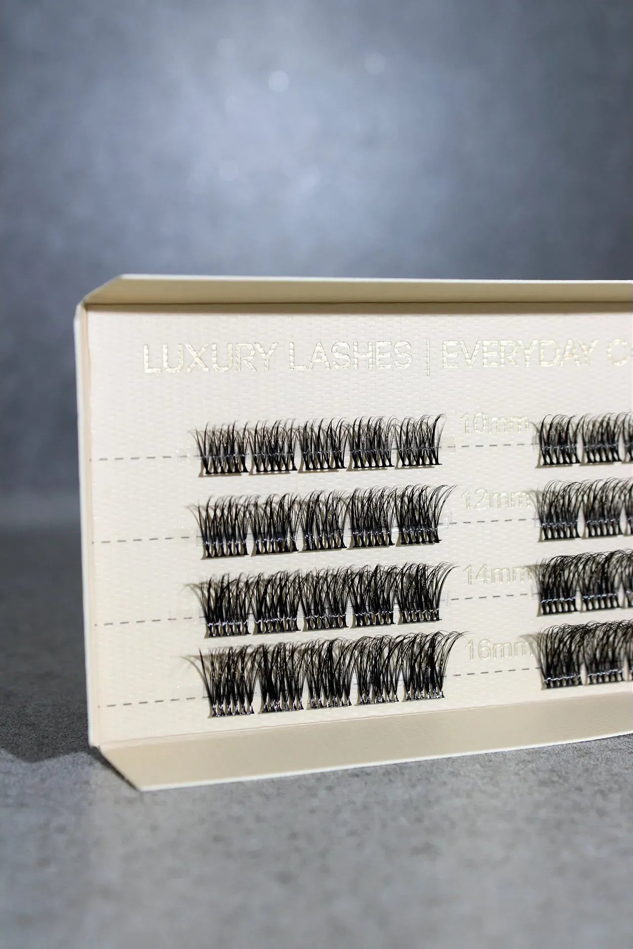 Eyelash extension box with multiple rows of lashes on a gray background