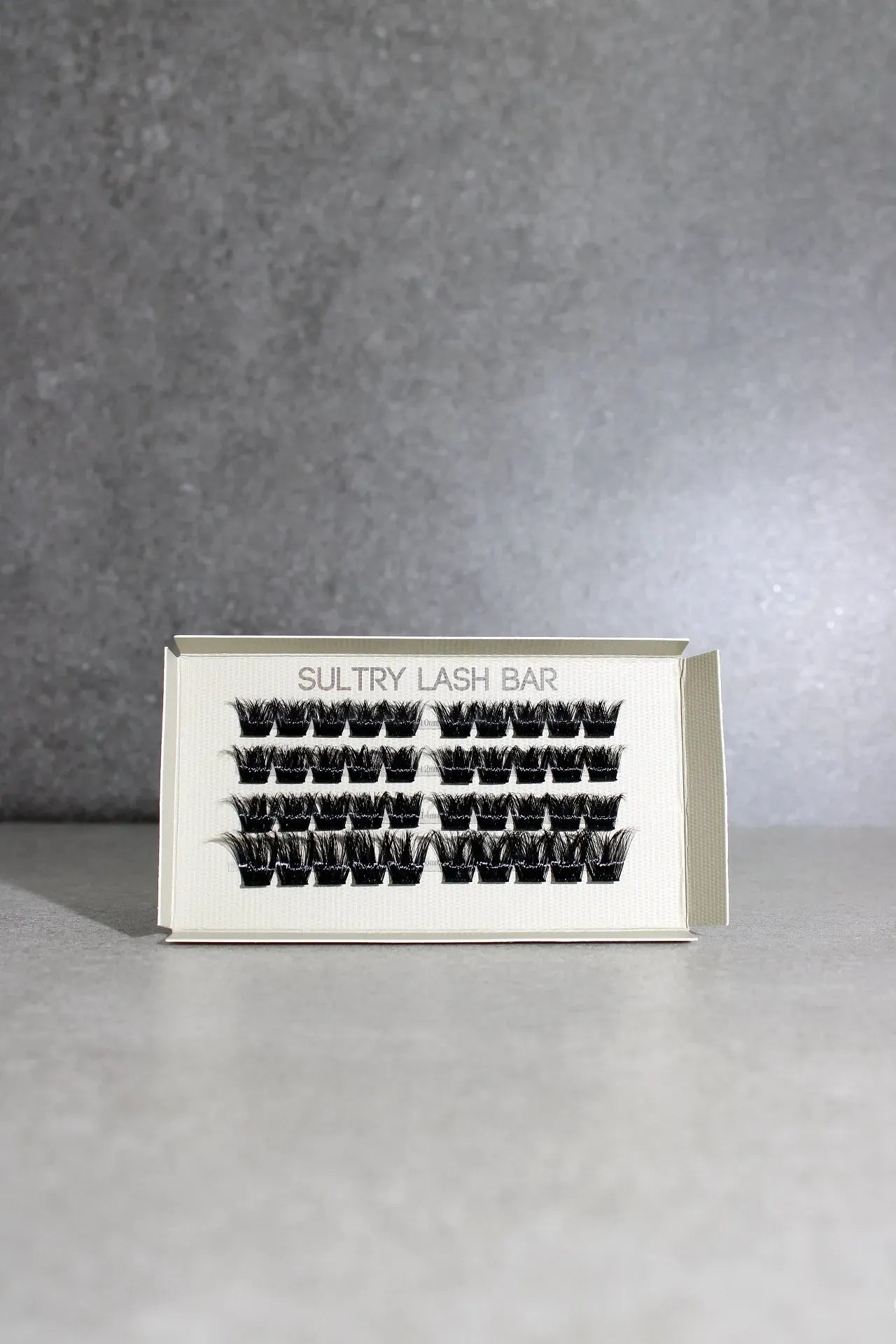 Eyelash extensions in a box with 'Sultry Lash Bar' branding on a gray background