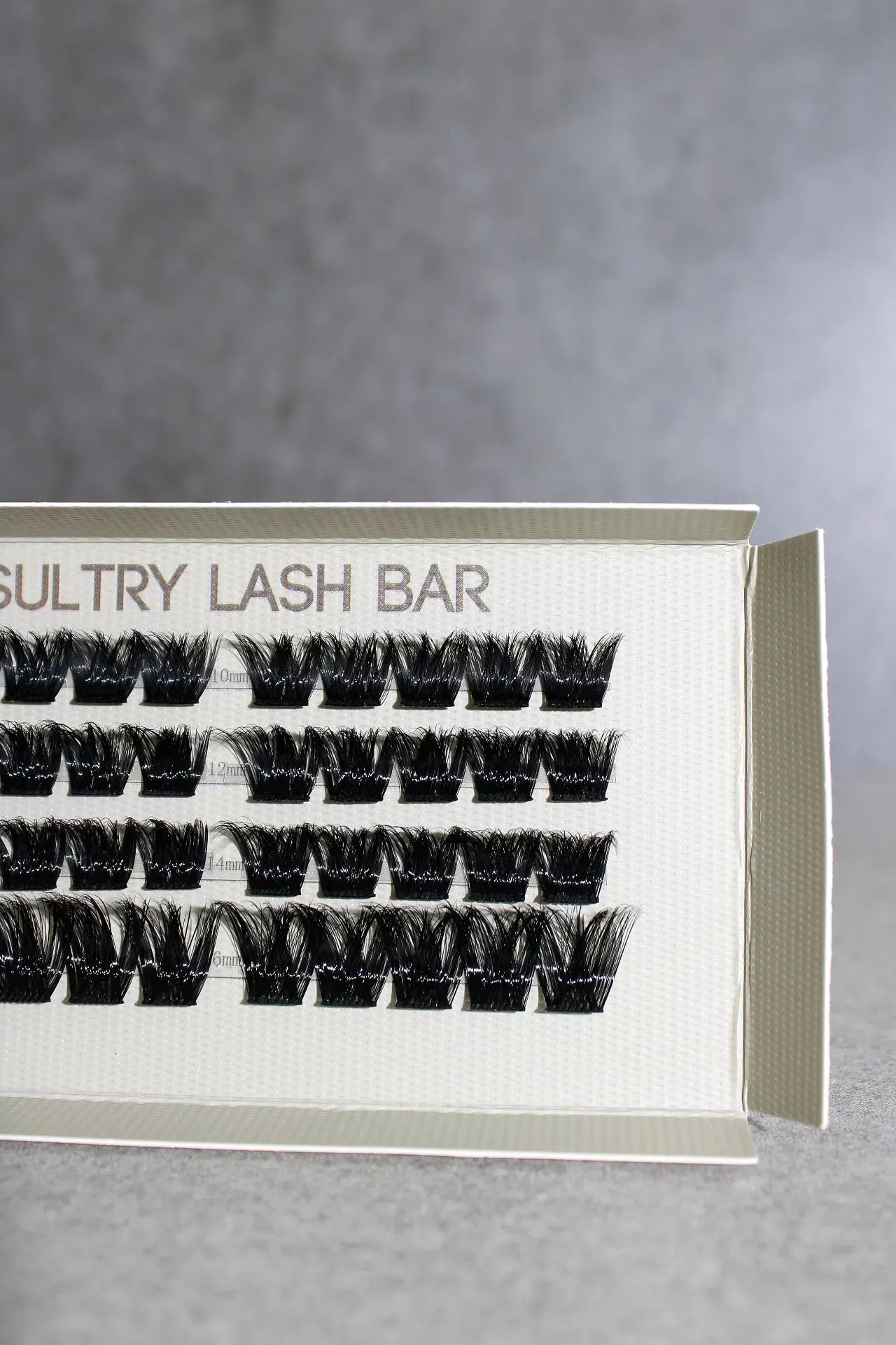 Eyelash extensions in a box with 'Sultry Lash Bar' branding on a gray background