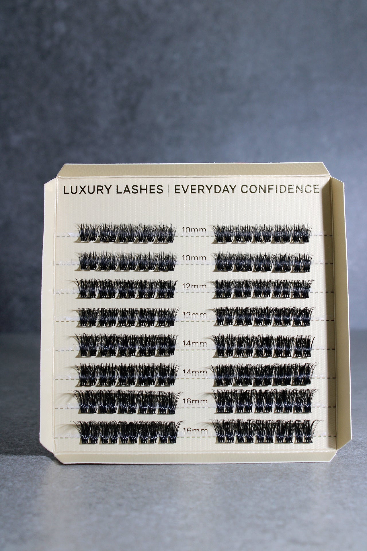 Eyelash extension tray with various lash lengths on a gray background