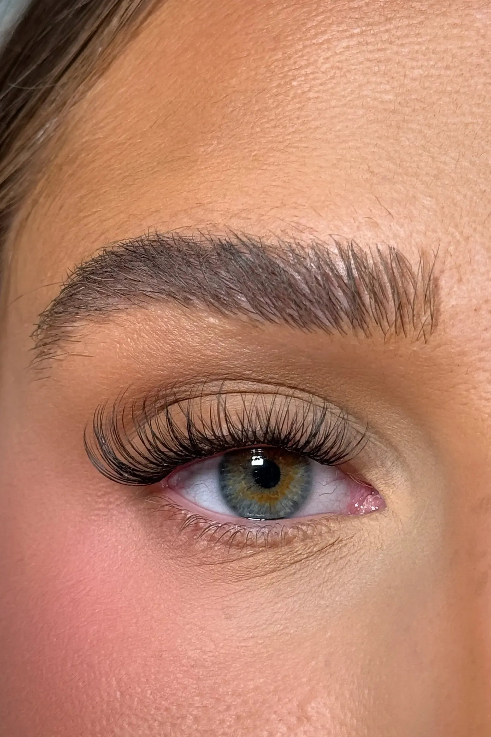 Close-up of a person's eye with long eyelashes and well-groomed eyebrow.