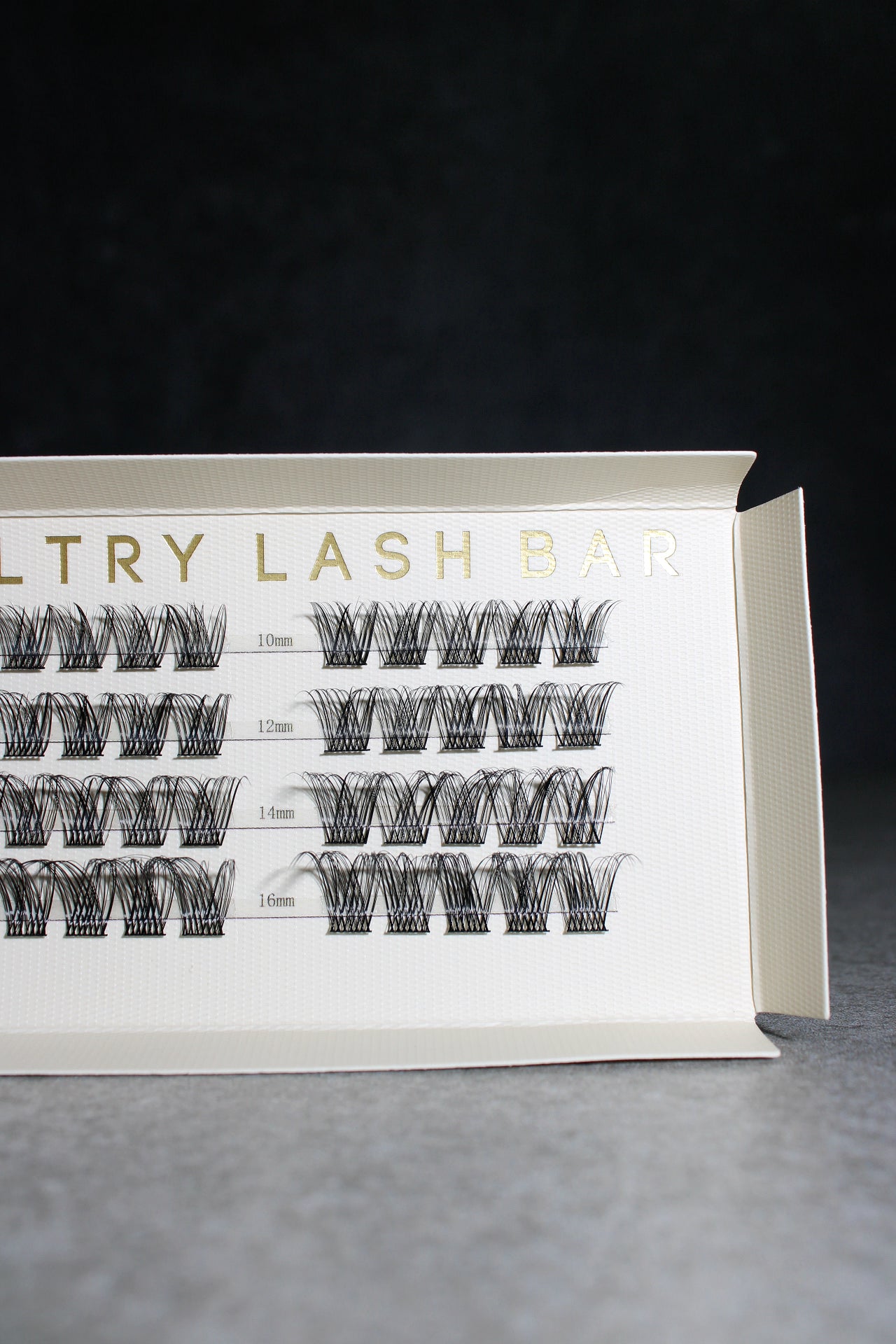 Eyelash extension tray with labeled rows on a dark background