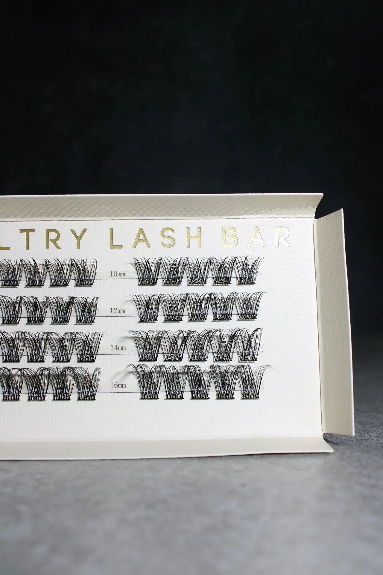 Eyelash extension tray with labeled rows on a dark background