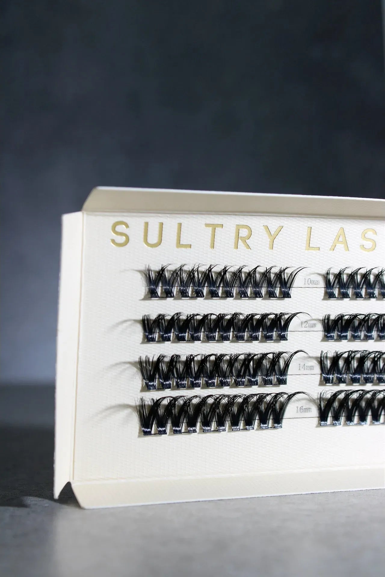 Eyelash extension tray with 'Sultry Lash' branding on a dark background
