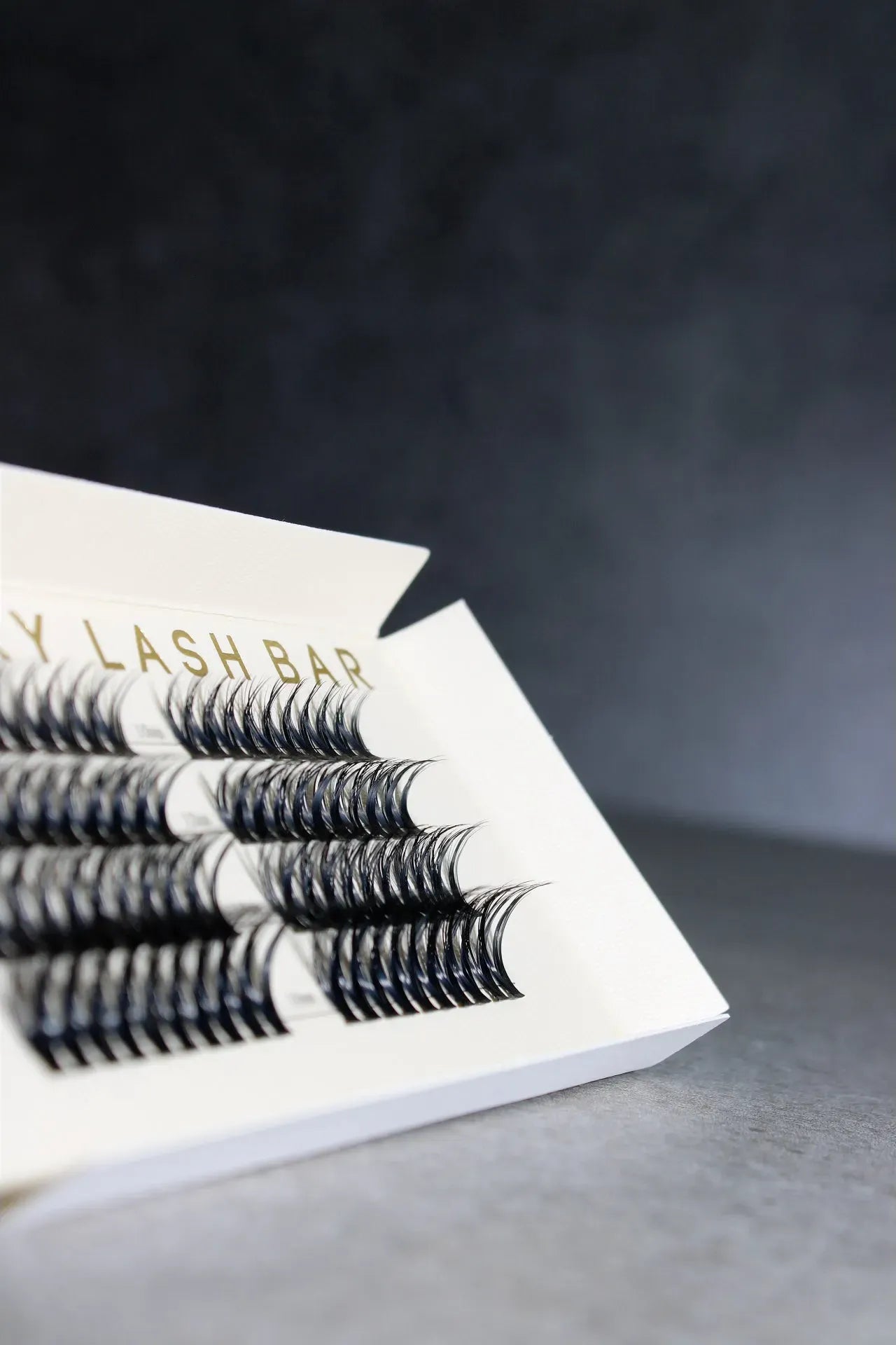 Eyelash extensions in a box with 'Lash Bar' branding on a dark background