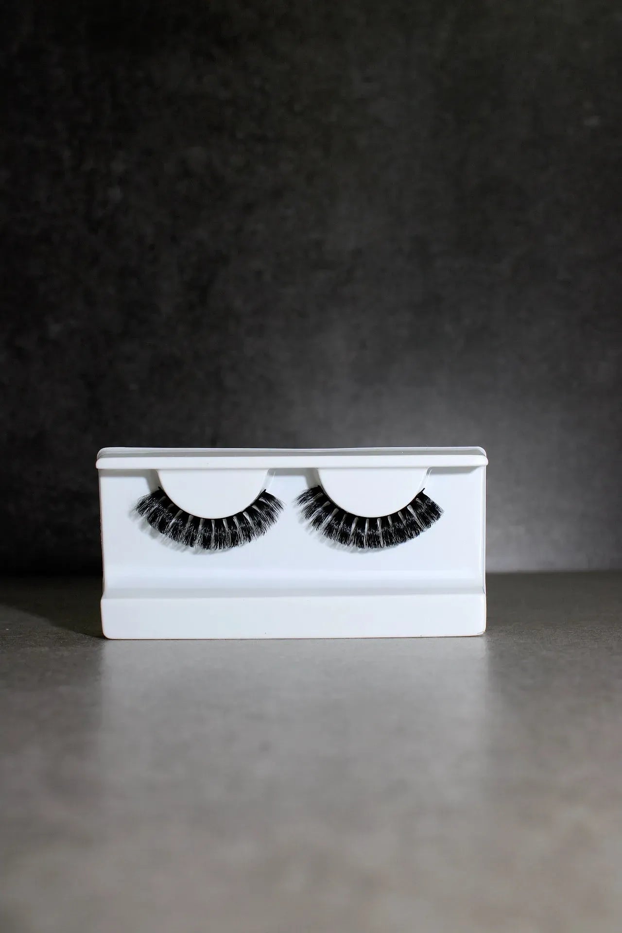 Pair of false eyelashes on a white card against a dark background