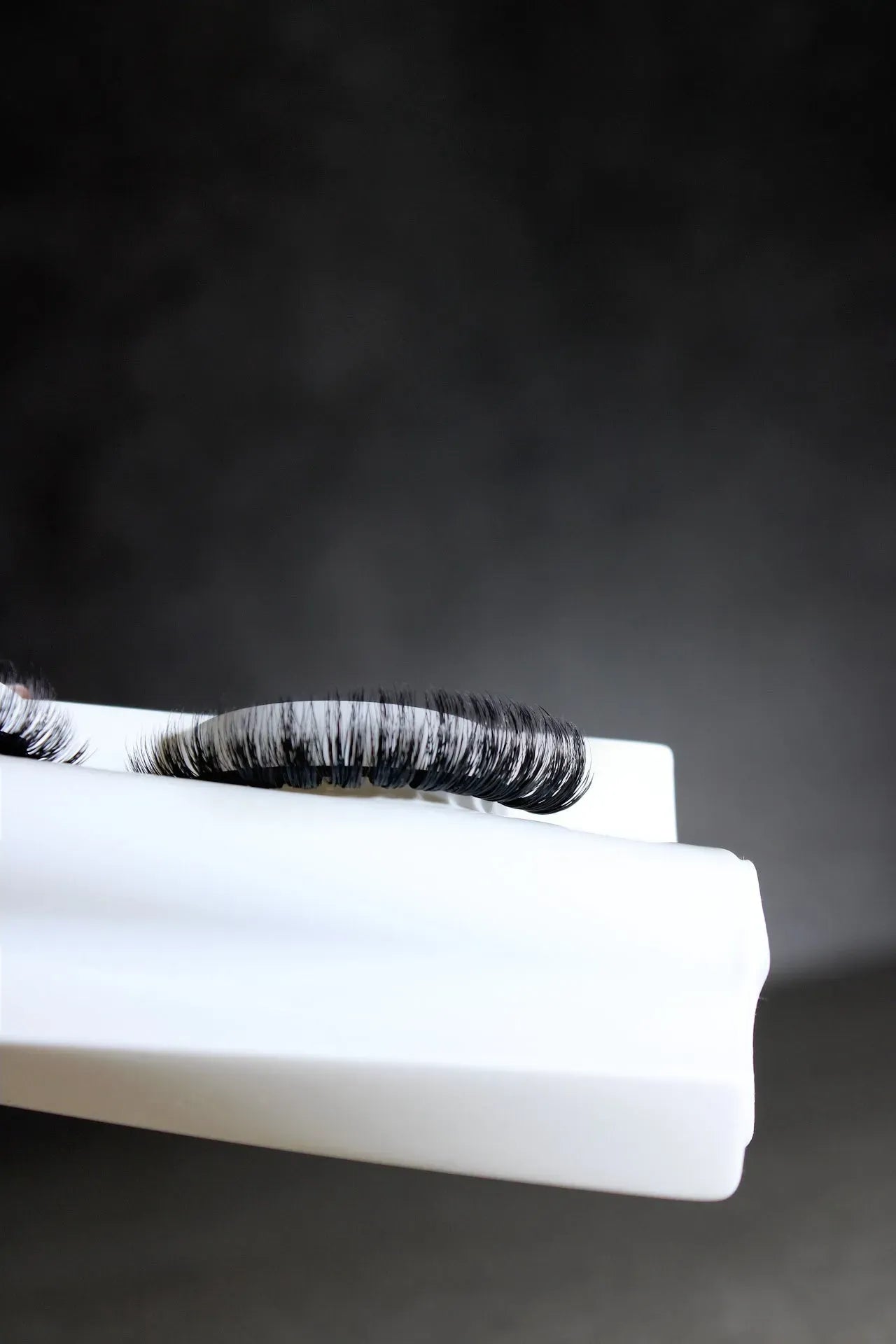 False eyelashes on a white surface with a dark background