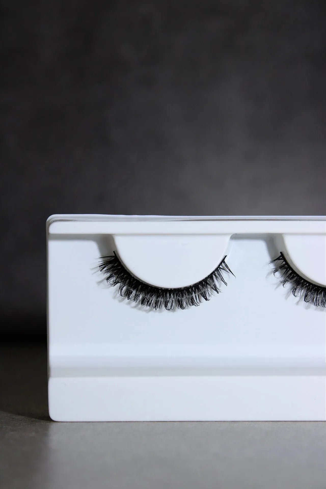 False eyelashes on a white tray against a dark background