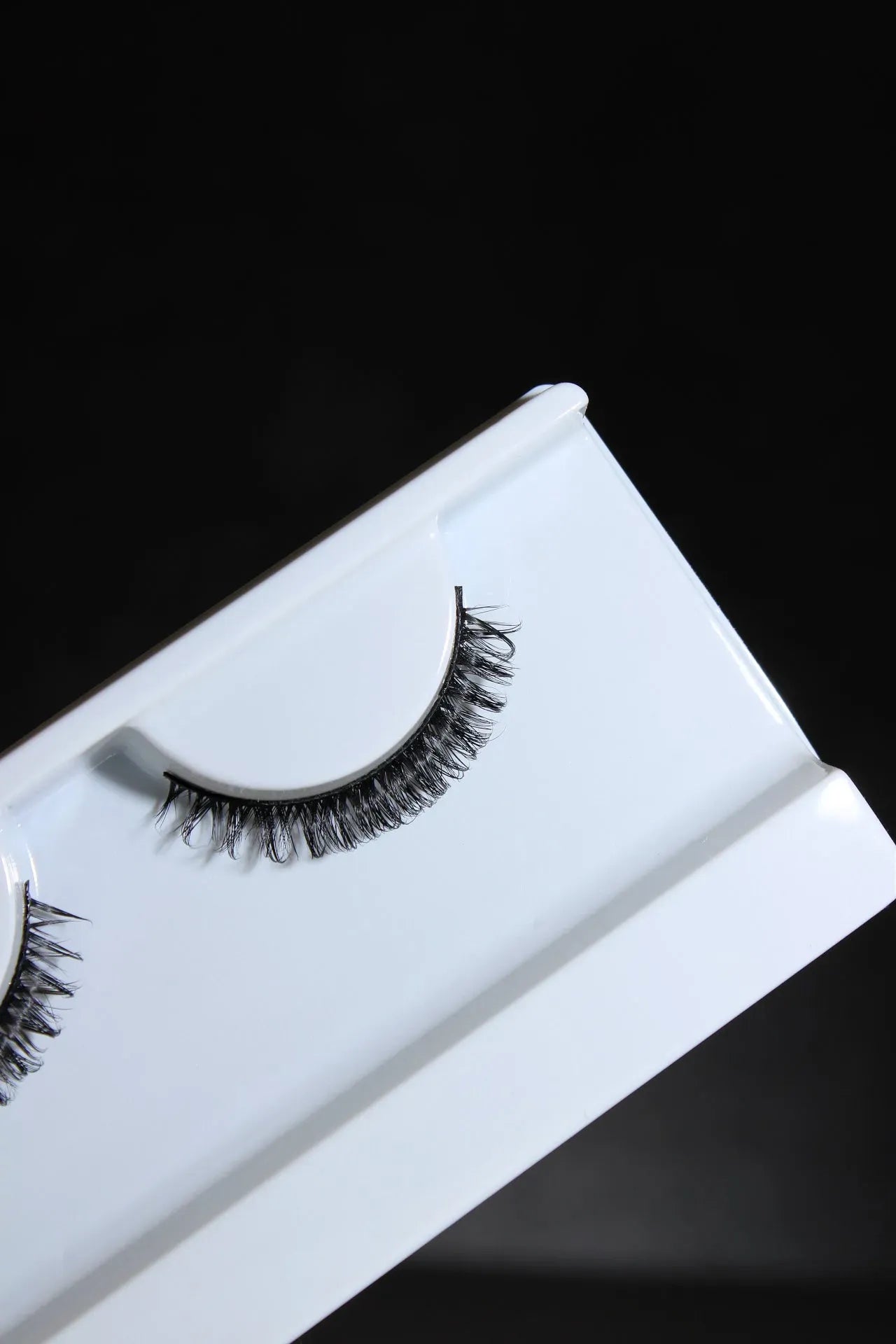 False eyelashes on a white tray against a black background