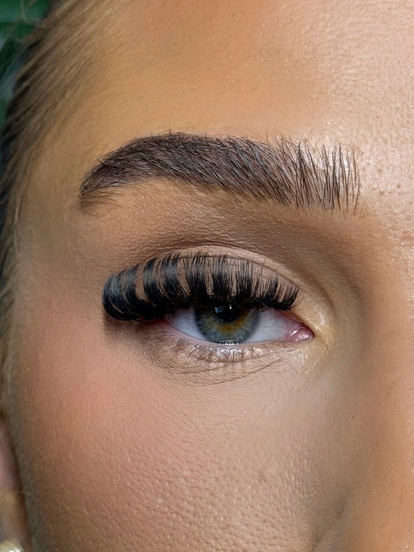 Close-up of a person's eye with long, dark eyelashes and well-groomed eyebrow.