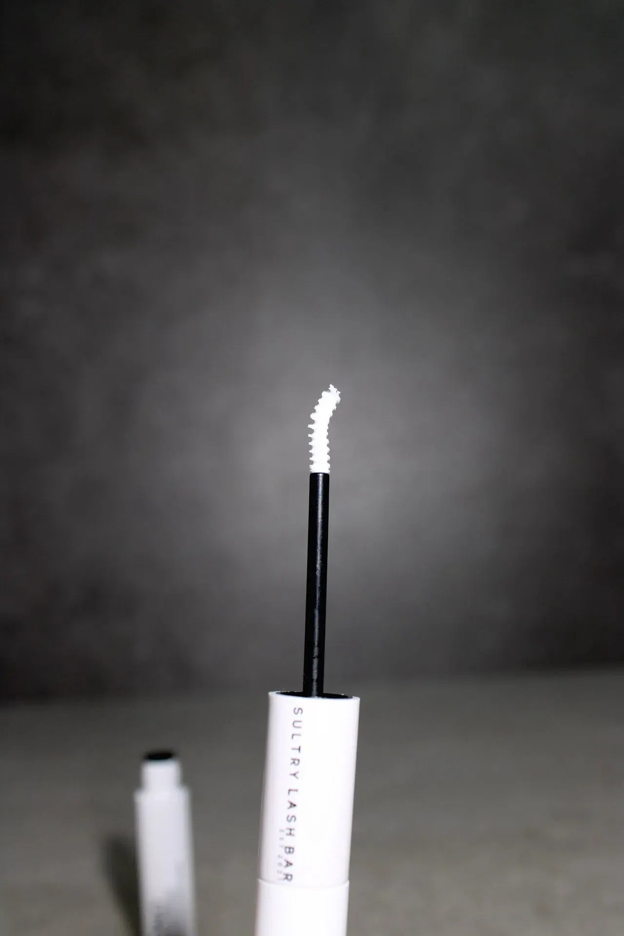 eyelash adhesive with white cap on a dark background