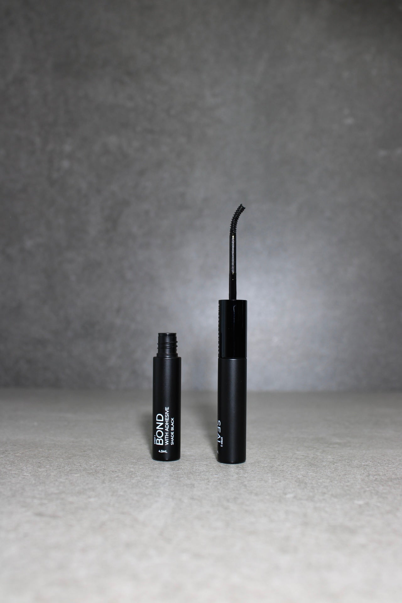 Two black cosmetic products with 'BOND' branding on a gray background