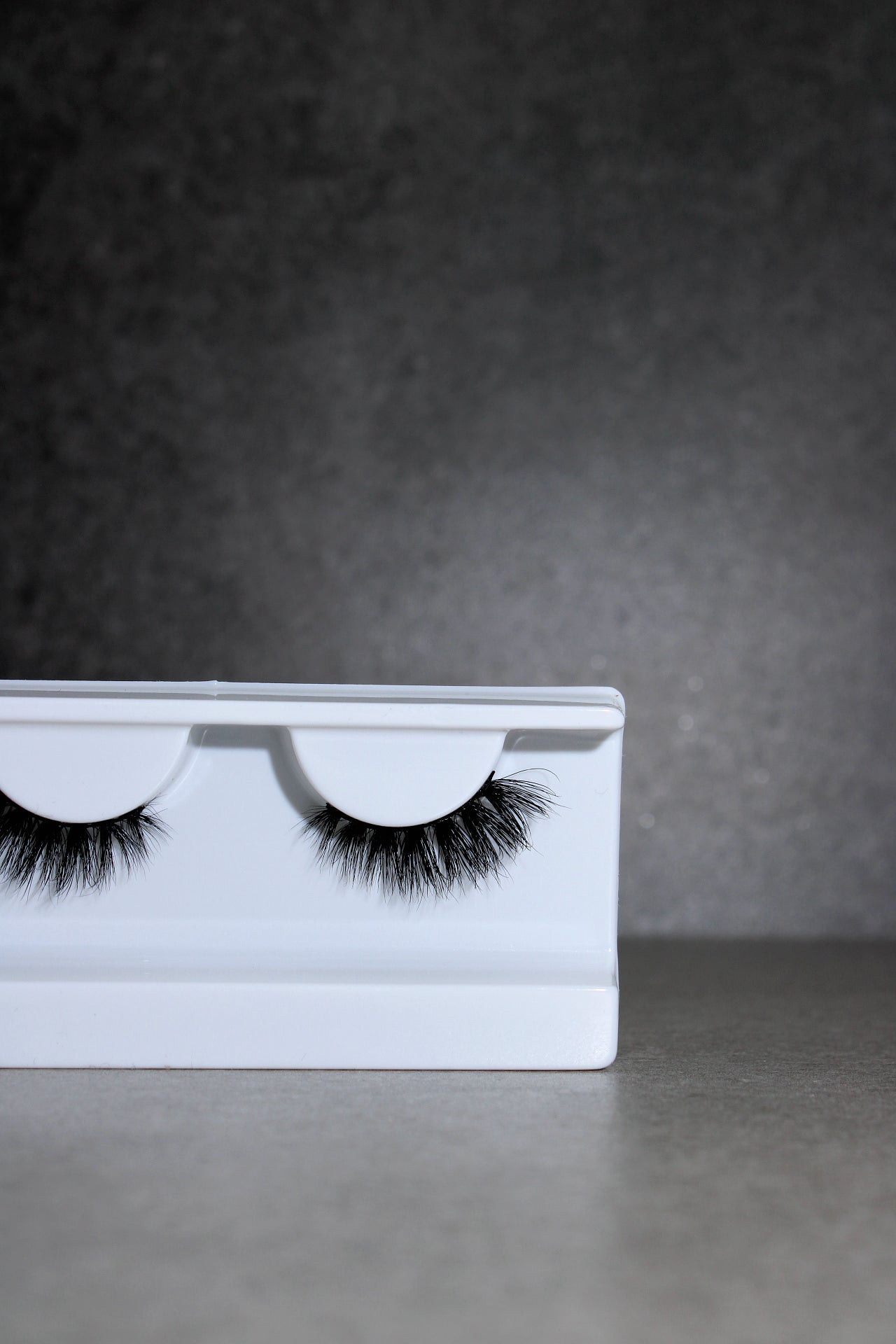 Eyelash packaging with false eyelashes on a gray background