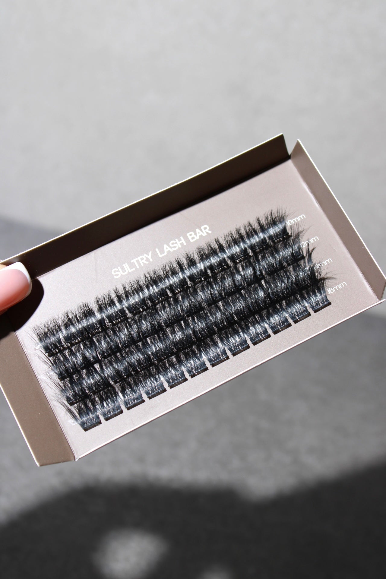 Close-up of SL20 Korean fibre hair C curl DIY single cluster lash extensions, neatly arranged in a box with varying lengths for a customizable lash look.