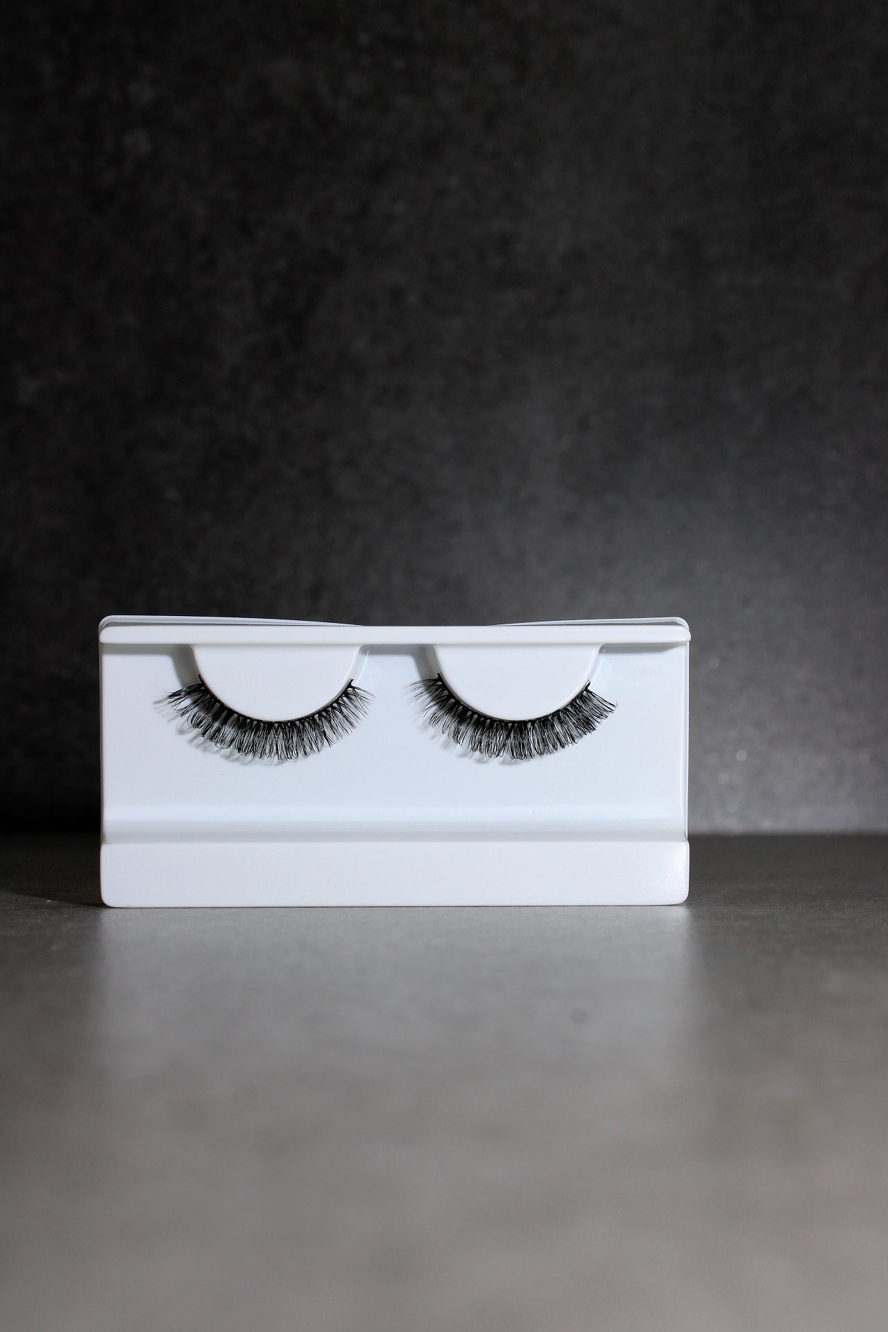 Pair of false eyelashes on a white card against a dark background