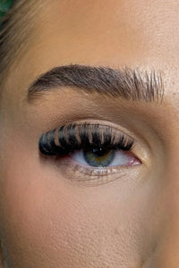 Close-up of a person's eye with long, dark eyelashes and well-groomed eyebrow.
