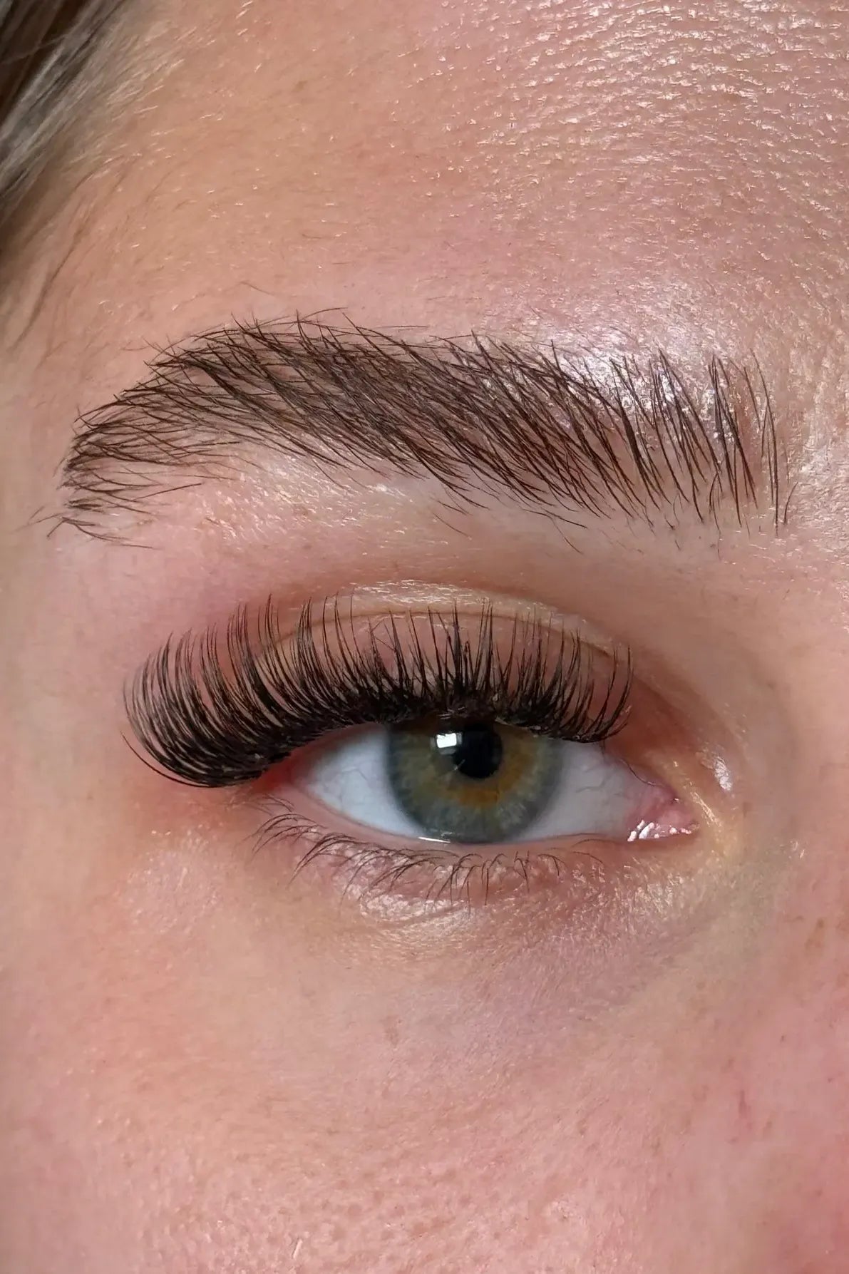 Close-up of a person's eye with long, dark eyelashes and well-groomed eyebrow.