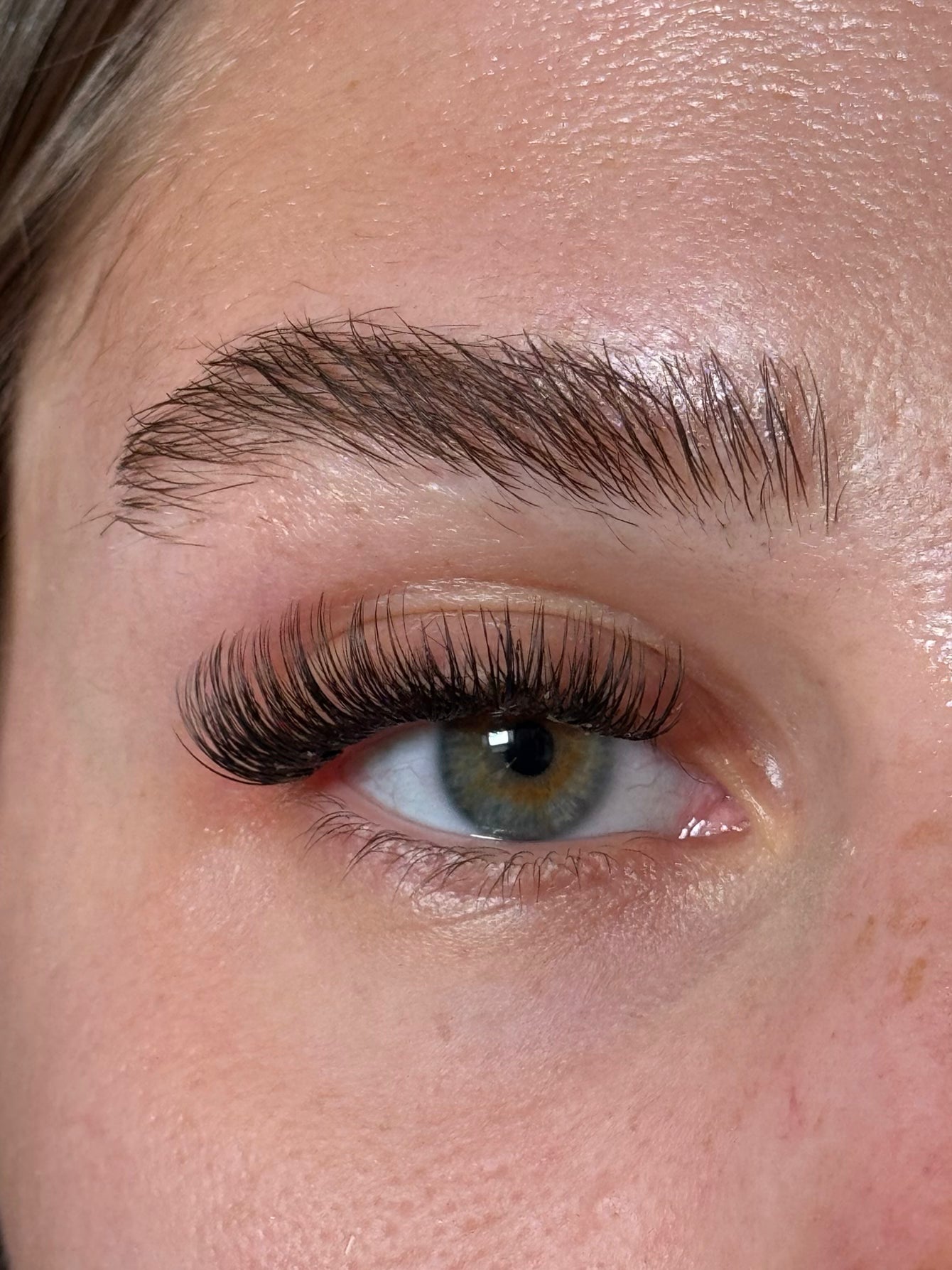 Close-up of a person's eye with long, dark eyelashes and well-groomed eyebrow.
