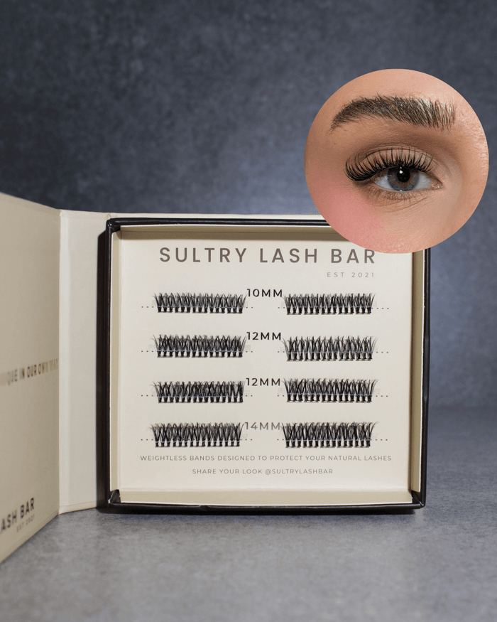 Sultry Lash Bar false eyelash bands displayed in an open black and cream box, with a circular inset showing a model's eye wearing the lashes. The box contains lash bands in 10mm, 12mm, and 4M lengths.