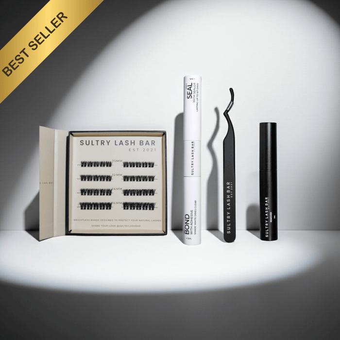 Eyelash products including a box of lashes, a tube of adhesive, and a curler on a white background.